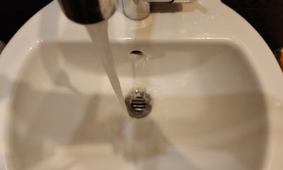 Струя воды из крана течёт в раковину, крупный план.