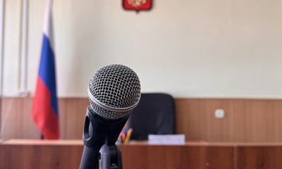 Микрофон на стойке в зале судебных заседаний с флагом и гербом России.